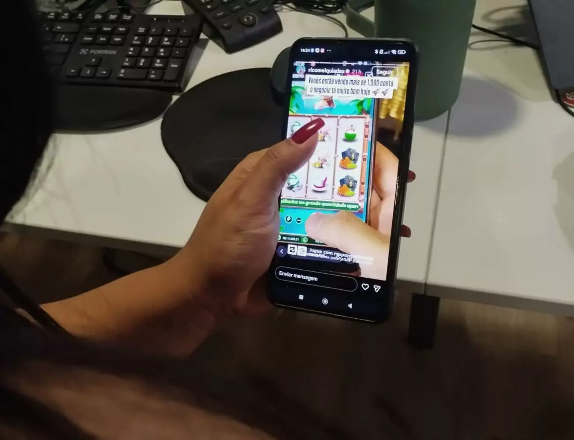 influenciadores que fazem publicidade irregular de bets mão com celular olhando aposta